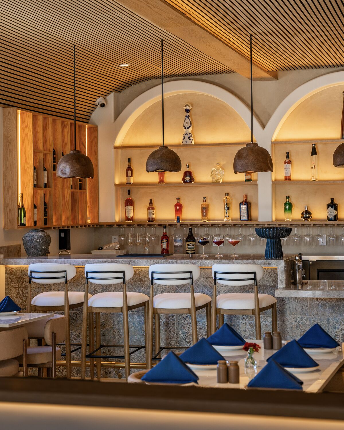 Arched bar with bar stools and set dining tables in Manhattan Beach