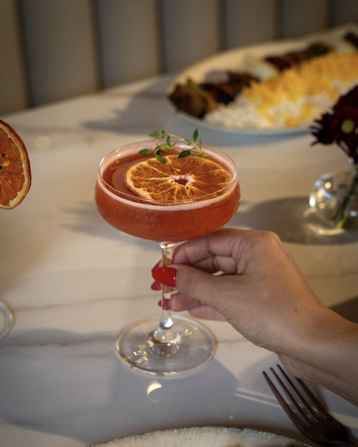 Cocktail garnished with dried orange and fresh thyme in Manhattan Beach