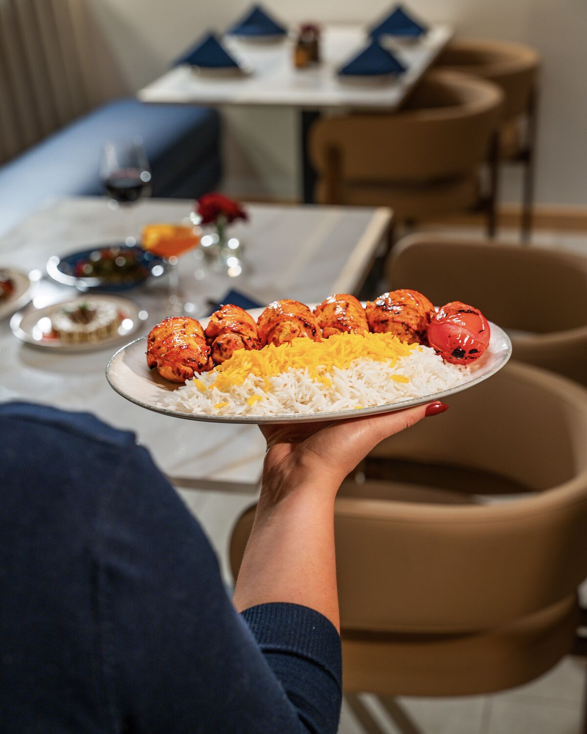 Server presenting a joojeh kabob plate with saffron rice in Manhattan Beach