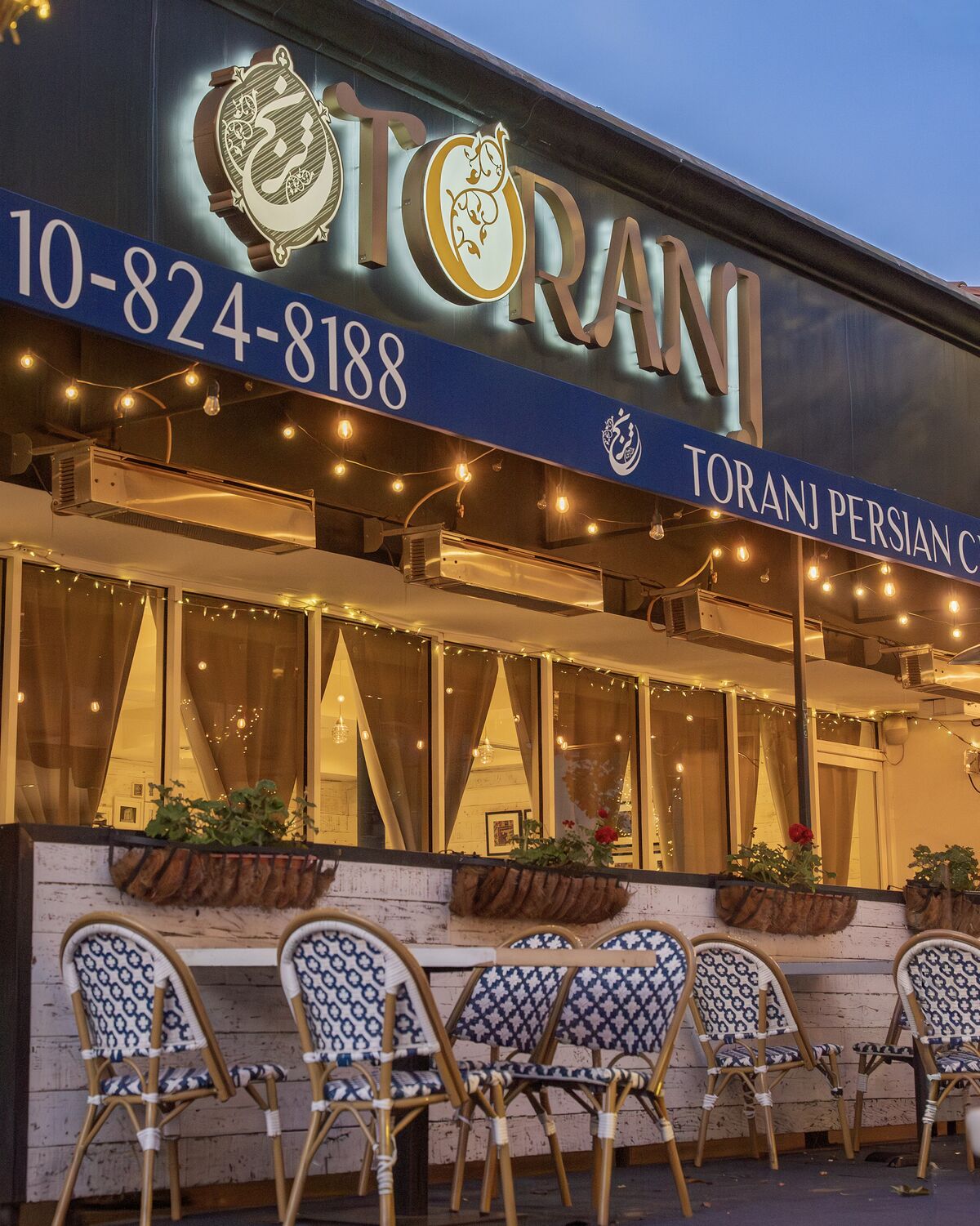 Lit Toranj storefront and sidewalk seating in Westwood Village at dusk in Westwood Village
