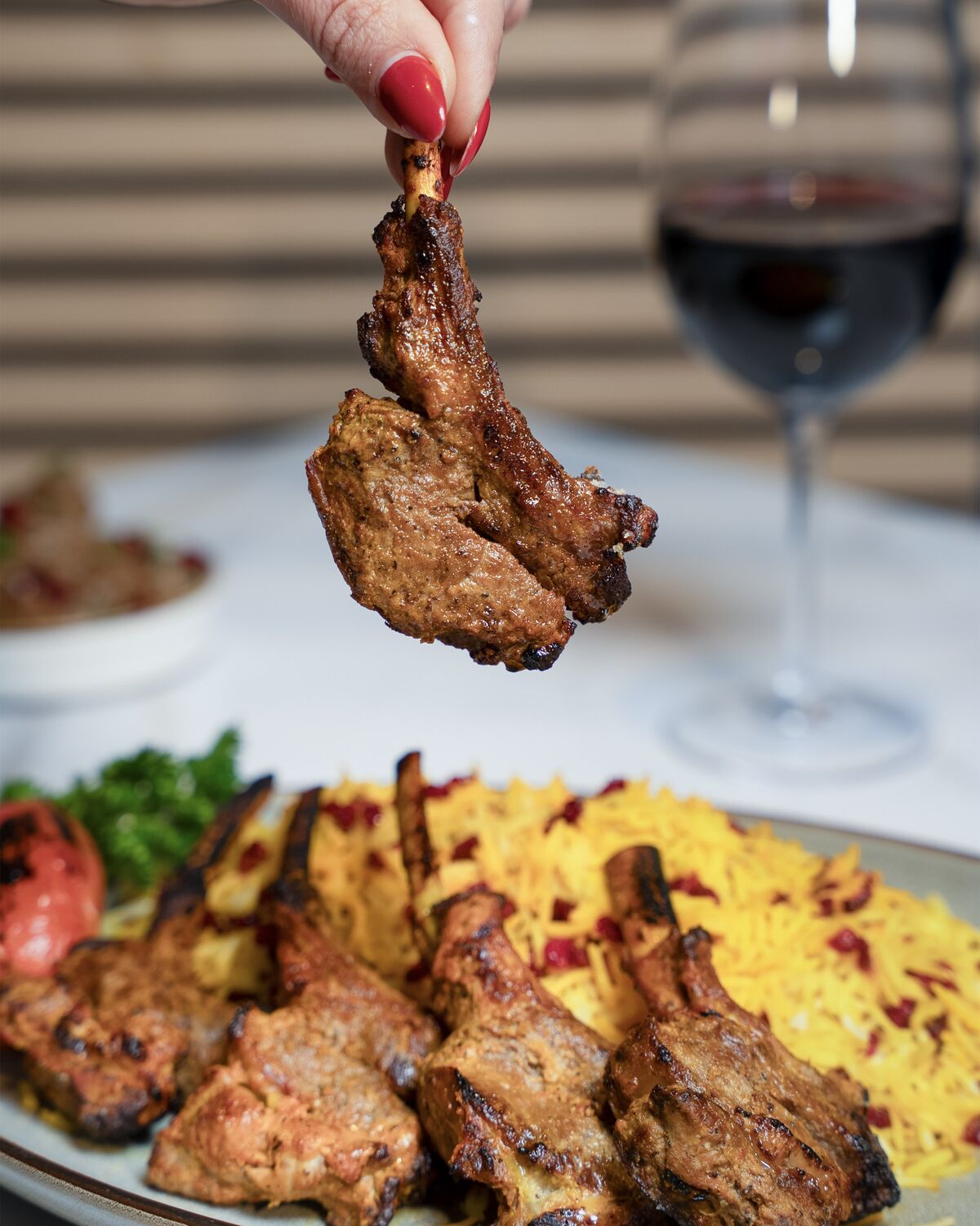 Fire-grilled lamb chop lifted from the platter in Westwood Village