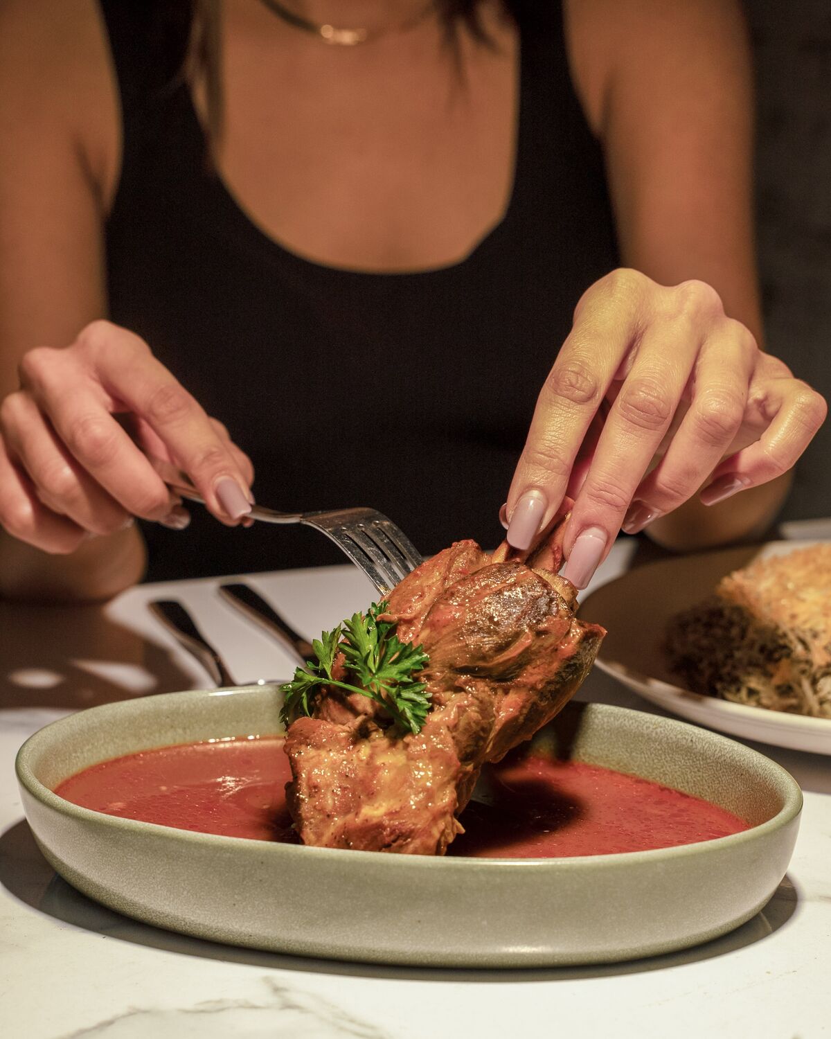 Guest serving braised lamb shank falling off the bone in Westwood Village